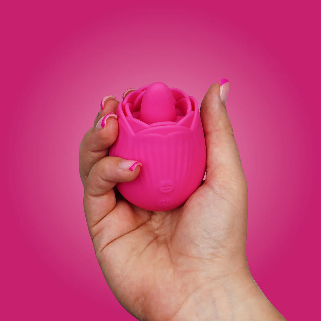 “Pink rose-shaped vibrator held in hand, showing compact size and soft silicone texture.