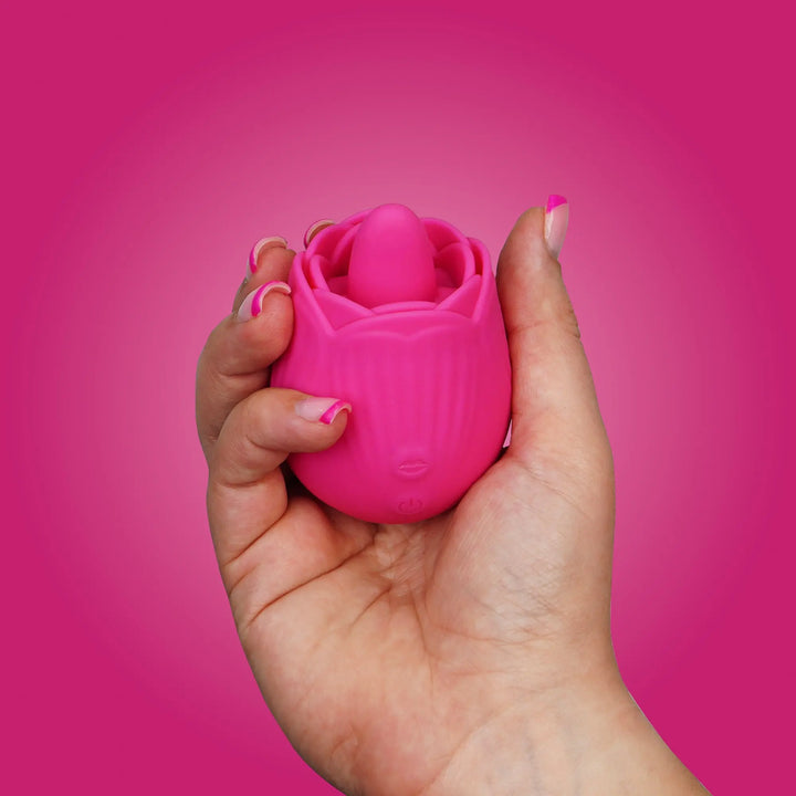 “Pink rose-shaped vibrator held in hand, showing compact size and soft silicone texture.