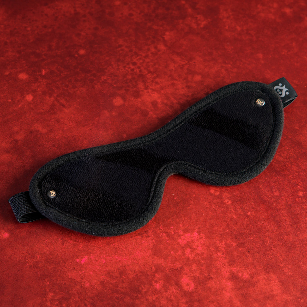 Black sleep mask on a red textured background