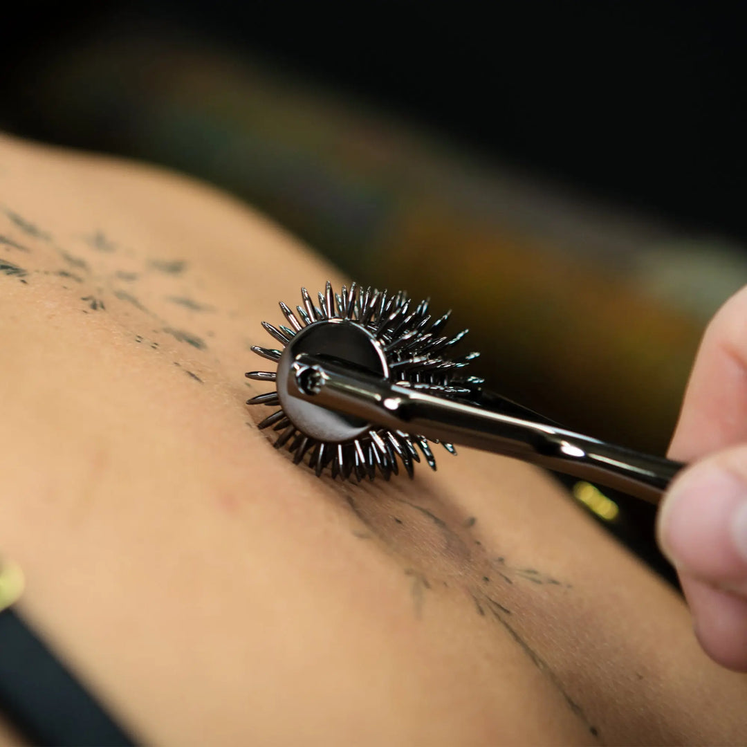 Person using a metal tool on their skin with a blurred background
