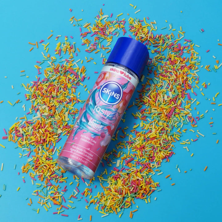 Skins birthday cake lube surrounded by colourful sprinkles on a blue background
