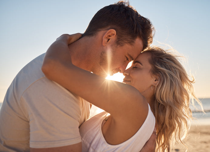 a female and male couple embracing each other on a sun-kissed beach